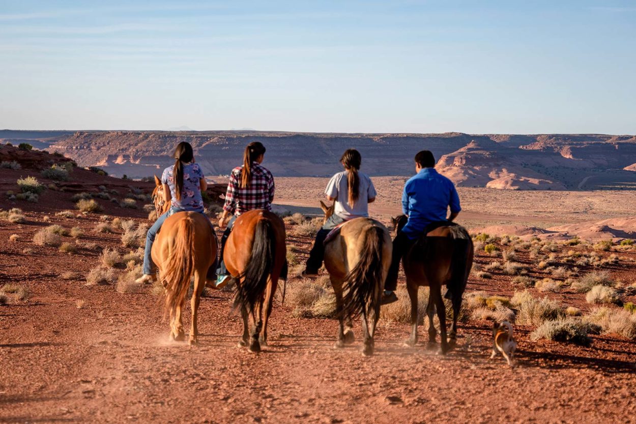 Group of young Navajo Siblings Riding Their horses Bareback through the vast desert in Northern Arizona near the Monument Valley Tribal park on the Navajo Indian Reservation at Dusk