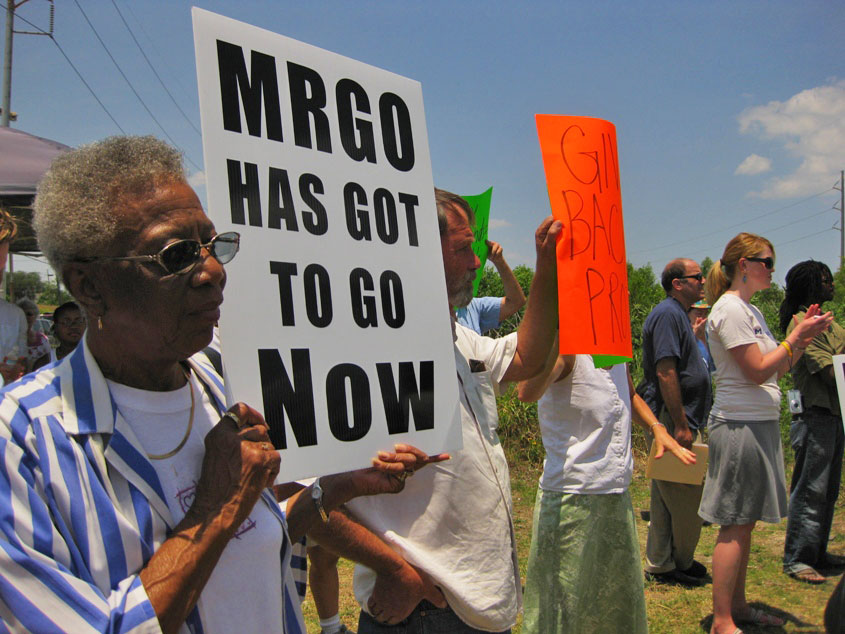 A protester holds a sign reading "MRGO has got to go now".