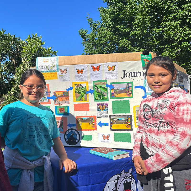 Students from Overton Elementary school in Austin showcase a colorful poster depicting the lifecycle of a butterfly.