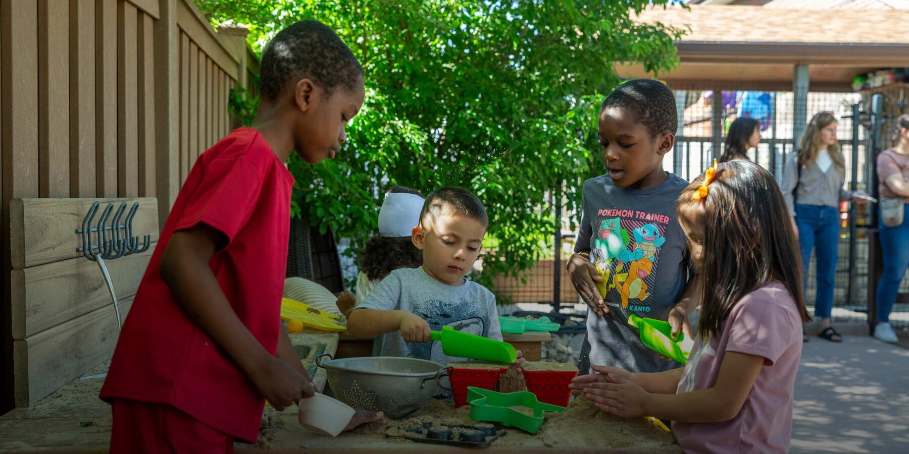 Kids play with sand and tools outdoors at the Little Giants Learning Center