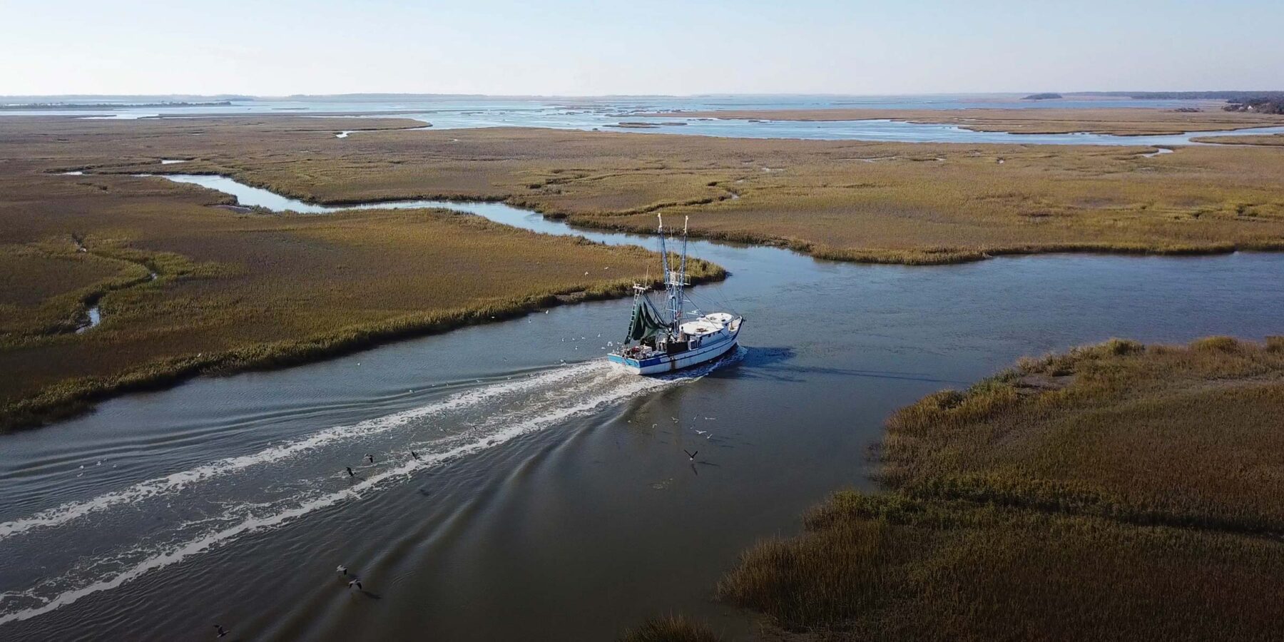 Aerial view of commercial fishing boat driving through marshy terrain in the Mississippi river