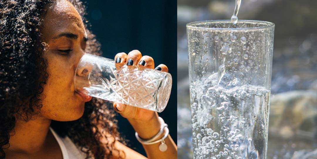 A woman drinks water out of a clear glass